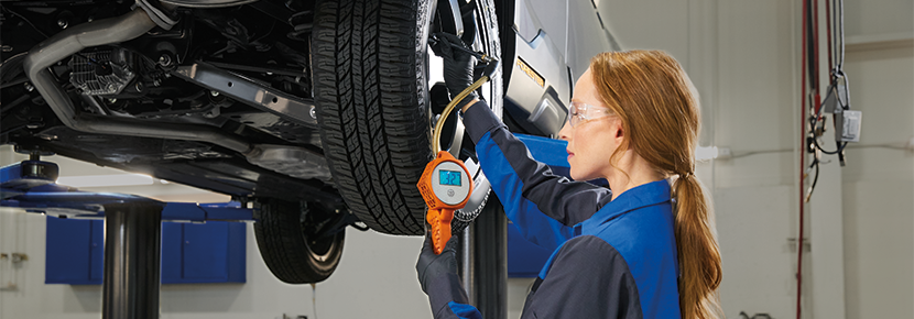 A Subaru technician checking tire pressure. | Empire Subaru of Huntington in Huntington NY