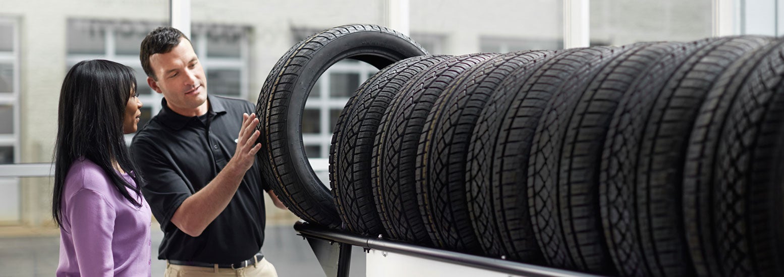 Subaru service representative showing customer a tire. | Empire Subaru of Huntington in Huntington NY